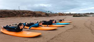 Un grupo de mujeres tumbadas sobre tablas de surf en la playa. en Freebird Surfcamp Morocco, en Agadir