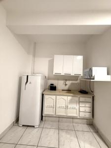 Una cocina con refrigerador y gabinetes blancos. en Smart Loft Premium Moderno e Inteligente no Centro Unidade 04, en Presidente Prudente