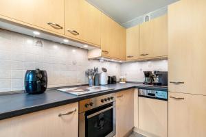 a kitchen with wooden cabinets and a black counter top at Kleine Auszeit am Meer in Büsum