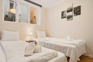 ein Zimmer mit drei Betten mit weißen Laken und einem Fenster in der Unterkunft Leiligheter i sentralt Bergenshus in Bergen