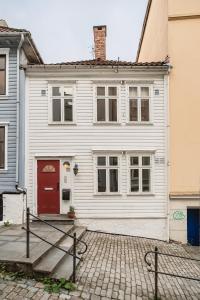 ein weißes Haus mit einer roten Tür in der Unterkunft Leiligheter i sentralt Bergenshus in Bergen