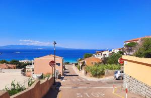 Una calle vacía con señales de stop y el océano. en Case Vacanza Santa Teresa Gallura, en Santa Teresa Gallura
