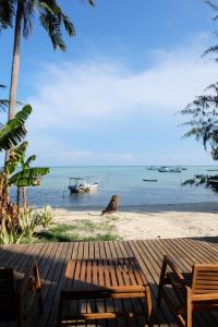 a bench on the beach with a boat in the water at Pulojava Resort in Karimunjawa
