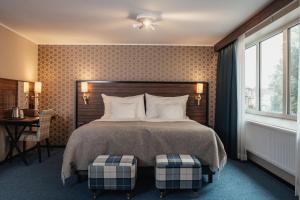 een slaapkamer met een bed, een bureau en een raam bij Home Hotel Slottsparken in Linköping