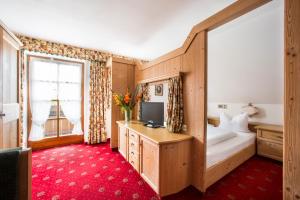 a bedroom with a bed and a desk with a tv at Hotel Hölzer Bräu by Lehmann Hotels in Ebersberg