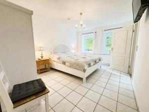 a white bedroom with a bed and a window at Krischan - ruhige FeWo mit Garten, nur 5 km zum Strand in Bönstrup