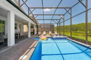 - une piscine intérieure dans une maison dotée d'un toit en verre dans l'établissement Great 8 br villa w games theater pool by Disney, à Kissimmee