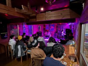 a group of people sitting in a bar watching a band at Shika Lodge in Iiyama