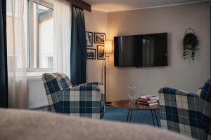 a living room with two chairs and a table and a television at Home Hotel Slottsparken in Linköping
