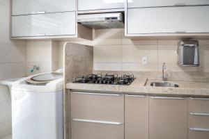 a kitchen with a stove and a sink at Point Convenience by Marzani Host in Goiânia