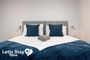 a bedroom with a bed with blue pillows at Morecambe Bay Stays in Morecambe