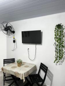 a dining room with a table and a tv on a wall at Brisa do Forte in São Francisco do Sul