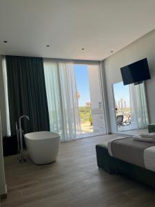 a bedroom with a tub and a bed and a large window at Lumeris lakeview Suites and SPA in Rubjekë