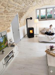 a man sitting on a couch in a living room with a wood stove at Maison authentique du Vexin in Théméricourt