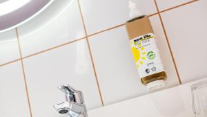 a bottle of sunscreen on the wall of a bathroom sink at greet Hotel Reims Tinqueux in Reims