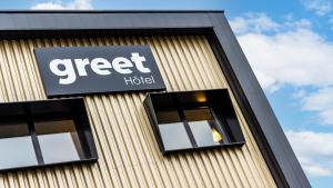a building with a sign for a greed hotel at greet Hotel Reims Tinqueux in Reims