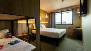 ein Hotelzimmer mit 2 Etagenbetten und einem Fenster in der Unterkunft greet Hotel Reims Tinqueux in Reims