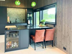 Una cocina con un mostrador y dos sillas en una barra. en Modern Cabin By The Lake In Kvelia,  16 fotos más
