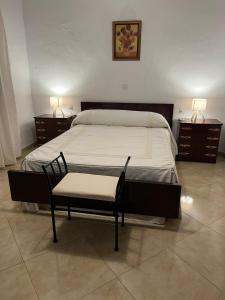 a bedroom with a bed with a chair and two night stands at Casa en la Huertecilla in Lora del Río