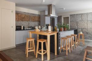 a kitchen with a wooden island with stools at Casa da Ponte in Amarante