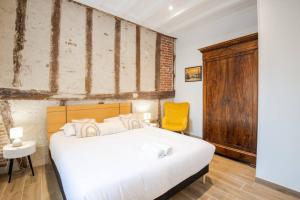 a bedroom with a white bed and a yellow chair at La Maison Renaissance Amboise 4 bedroom house in Amboise