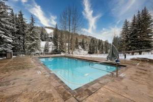 a swimming pool in a yard with snow covered trees at Ski In, Ski Out 3 Bedroom Condo At The Eagle Bahn Gondola With Slopeside Pool in Vail