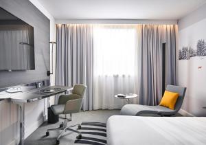 a hotel room with a bed and a desk and chairs at Novotel Leicester in Leicester +99 photos