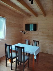 a dining room with a table and chairs and a television at Domki pod Klekotkiem in Smołdziński Las