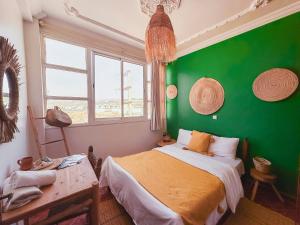 Dormitorio verde con cama y mesa en Freebird Surfcamp Morocco, en Agadir