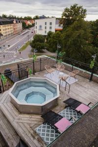 a hot tub on a deck with chairs and a street at Home Hotel Slottsparken in Linköping
