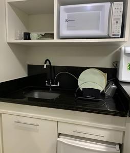 a kitchen counter with a sink and a microwave at Luxuoso Flat no Aldeia das Águas Com Vista para Piscina in Volta Redonda