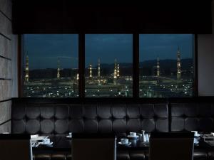 a restaurant with a view of a city from a window at Zamzam Pullman Madina in Al Madinah