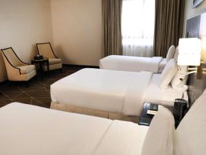 a hotel room with two beds and two chairs at Pullman Zamzam Madina in Al Madinah +144 photos