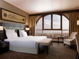 a bedroom with a large bed and a large window at Pullman Zamzam Madina in Al Madinah