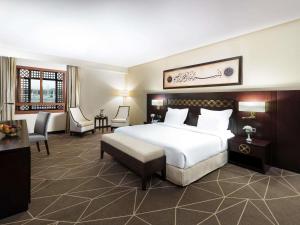 a hotel room with a bed and a desk and chairs at Zamzam Pullman Madina in Medina +128 photos
