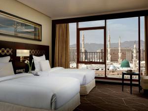 a hotel room with two beds and a large window at Zamzam Pullman Madina in Al Madinah