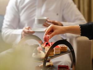 a person reaching for a piece of cake on a table at Zamzam Pullman Madina in Al Madinah