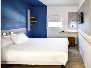 a bedroom with a white bed and a blue wall at ibis Budget Le Treport Mers Les Bains in Mers-les-Bains +43 photos