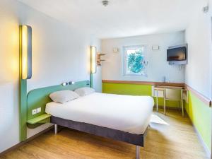 a bedroom with a white bed and a tv at Ibis Budget Chalon Sur Saone Nord in Chalon-sur-Saône +43 photos