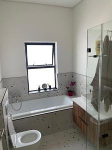 a bathroom with a tub and a toilet and a window at Sunny Side Haven in Faure +4 photos