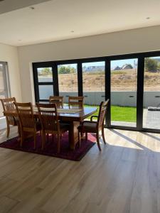 a dining room with a table and chairs and windows at Sunny Side Haven in Faure