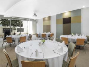 a dining room with white tables and chairs at The Sebel Maroochydore in Maroochydore