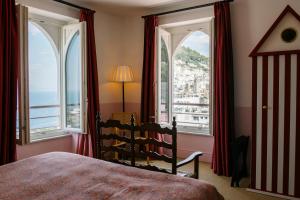 a bedroom with a bed and two large windows at Il Capri Hotel in Capri