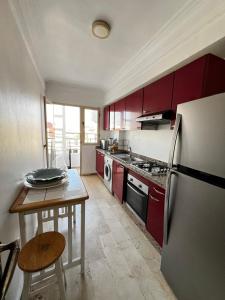 a kitchen with red cabinets and a table and a refrigerator at Corniche Casablanca in Casablanca