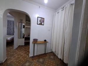 a hallway with a table in a room with white curtains at Joy's One Bedroom Apartment in Kitale