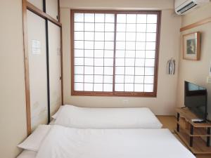 two beds in a room with a large window at 鶴の宿 那覇-国際通りまで950mの便利な立地-1棟貸切 in Naha