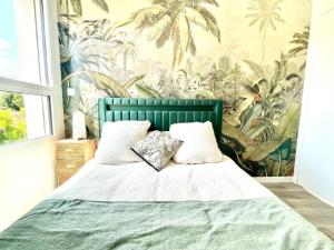 a bedroom with a bed with a tropical wallpaper at Jungle, chambre spacieuse au coeur des sables in Les Sables-dʼOlonne