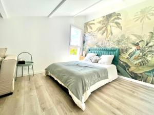 a bedroom with a bed with a painting on the wall at Jungle, chambre spacieuse au coeur des sables in Les Sables-dʼOlonne