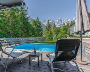 a deck with a chair and an umbrella next to a pool at Cassa Midas by the forest in Zgornje Jezersko
