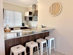 een keuken met een aanrecht met krukken en een klok aan de muur bij 105 Gouriqua Mosselbay in Mosselbaai